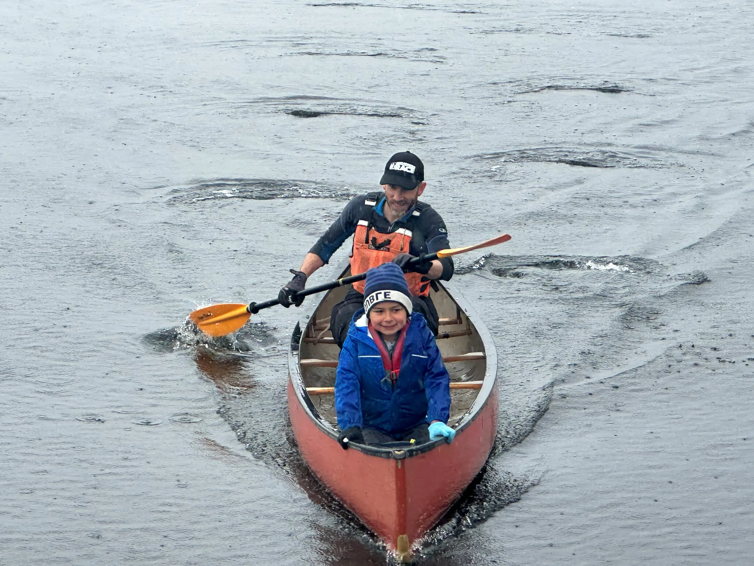 An adult and a young paddler in a red canoe at the 2026 Rankin River Canoe Rally